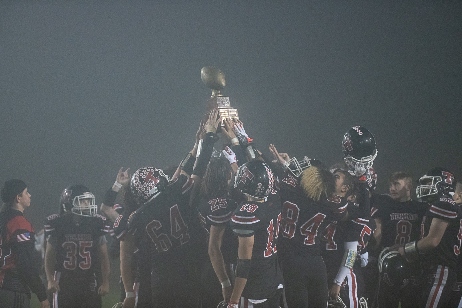 Tenino's football team holds up the Scatter Creek Showdown trophy after defeating Rochester 46-16 Oct. 28.