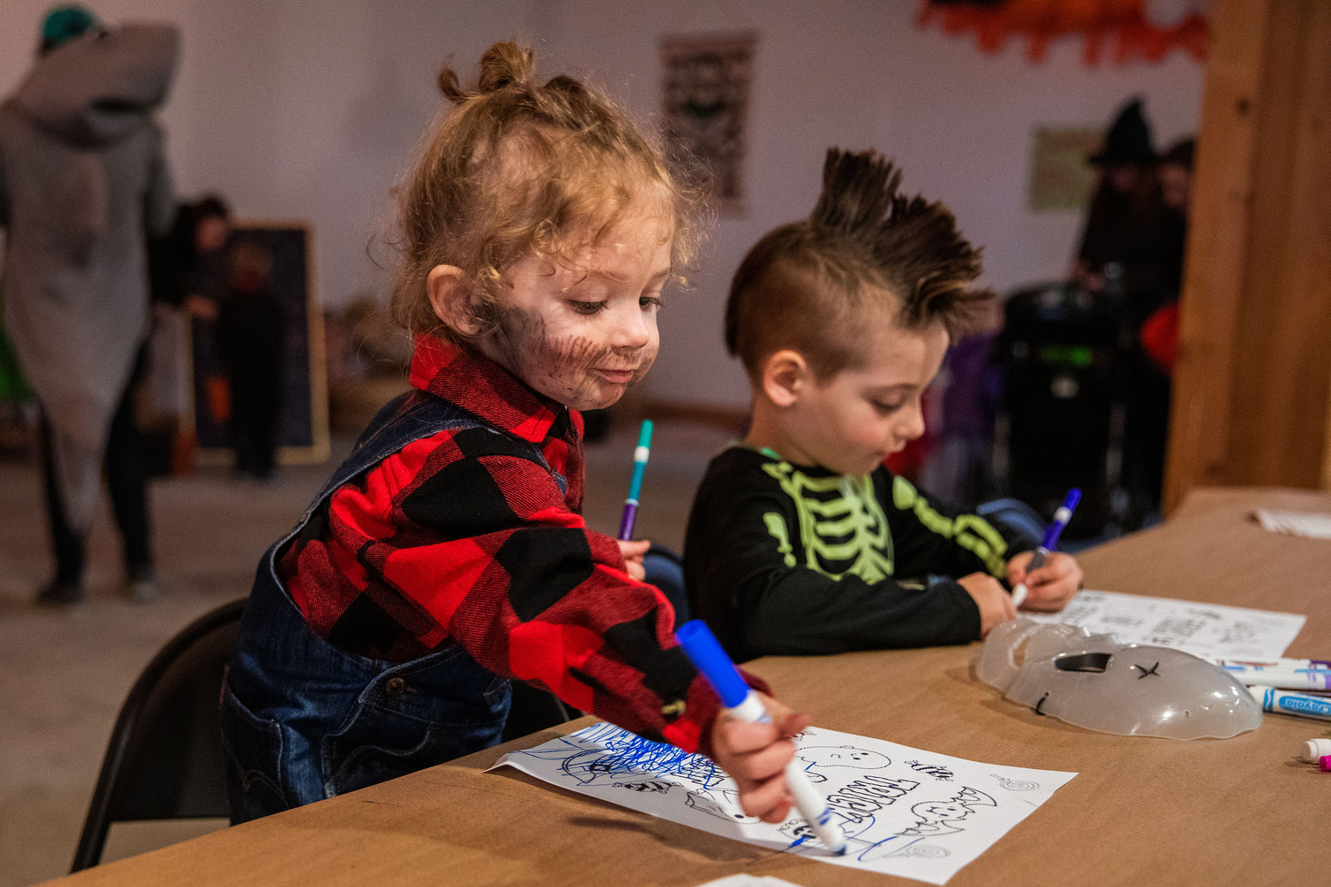 Kids draw over spooky characters during a Halloween Carnival at The White Space in downtown Centralia on Monday.