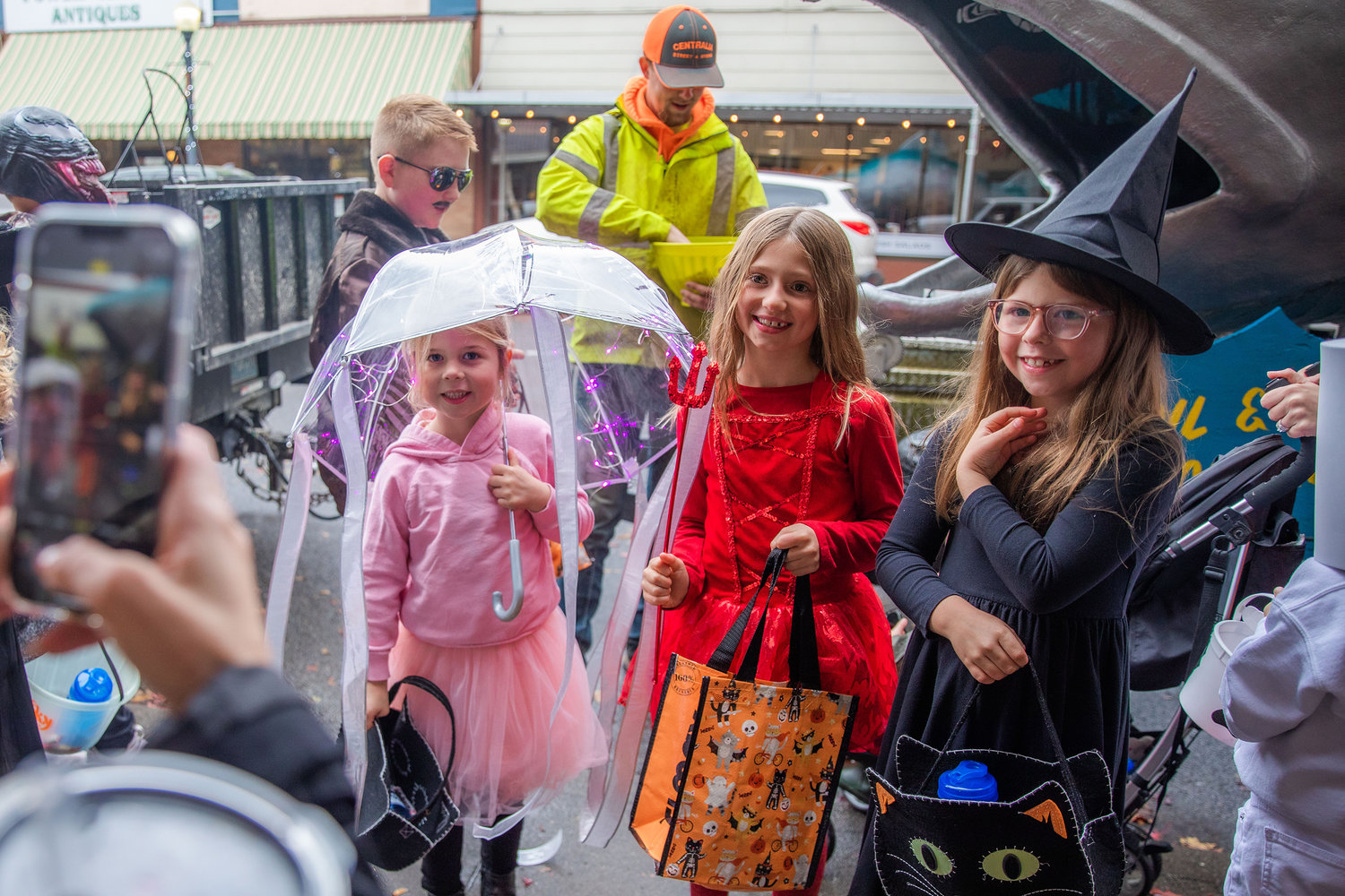 From left, Kate Ward, 6, Kynsley Noren, 8, and Josie Ward, 8, smile for a photo in downtown Centralia on Halloween.