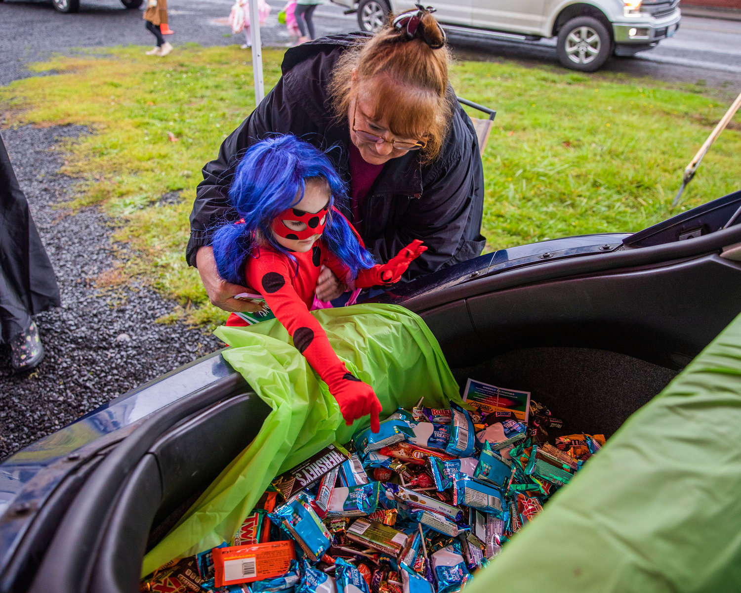 Children are helped to a trunk full of candy during Egg-O-Lantern festivities in Winlock on Halloween.