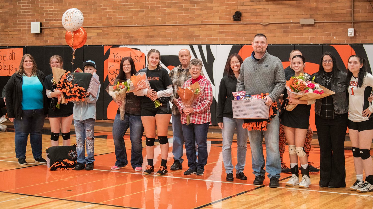 Seniors Maddie Buchanan, Tatum Johnston and Peyton Smith smile for a photo with family and Head Coach Marti Smith Thursday night at Centralia High School.