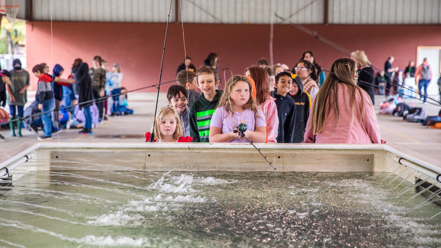 Students smile as they await their turn to fish for trout at Morton Elementary on Monday.