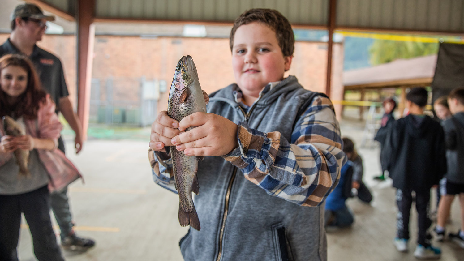 Students at Morton Elementary smile while holding up trout from a hatchery on Monday.