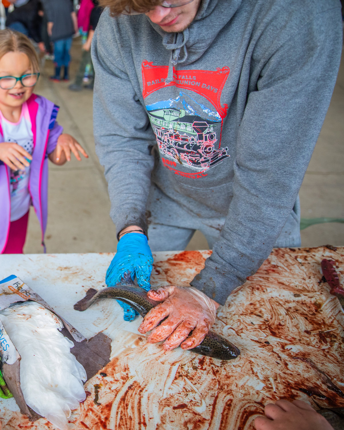 Students hold down flopping trout on a table before cutting off their heads at Morton Elementary on Monday.