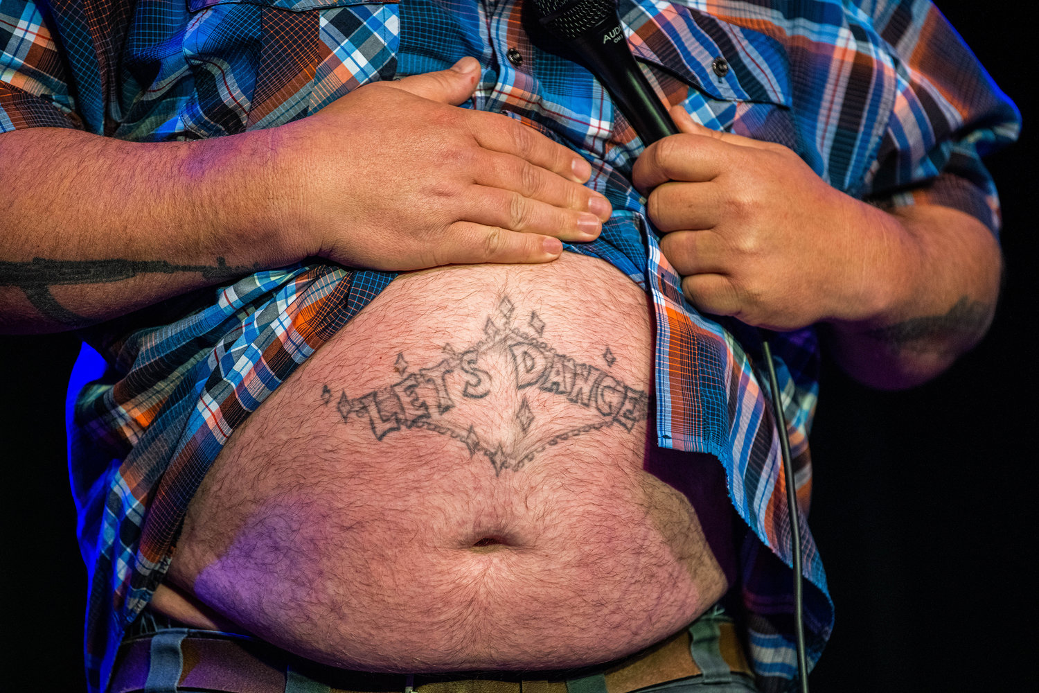 Local favorite Sam Miller shows off his stomach tattoo which reads, “Let’s Dance,” Friday night at the McFiler’s Chehalis Theater during a sold out comedy show.