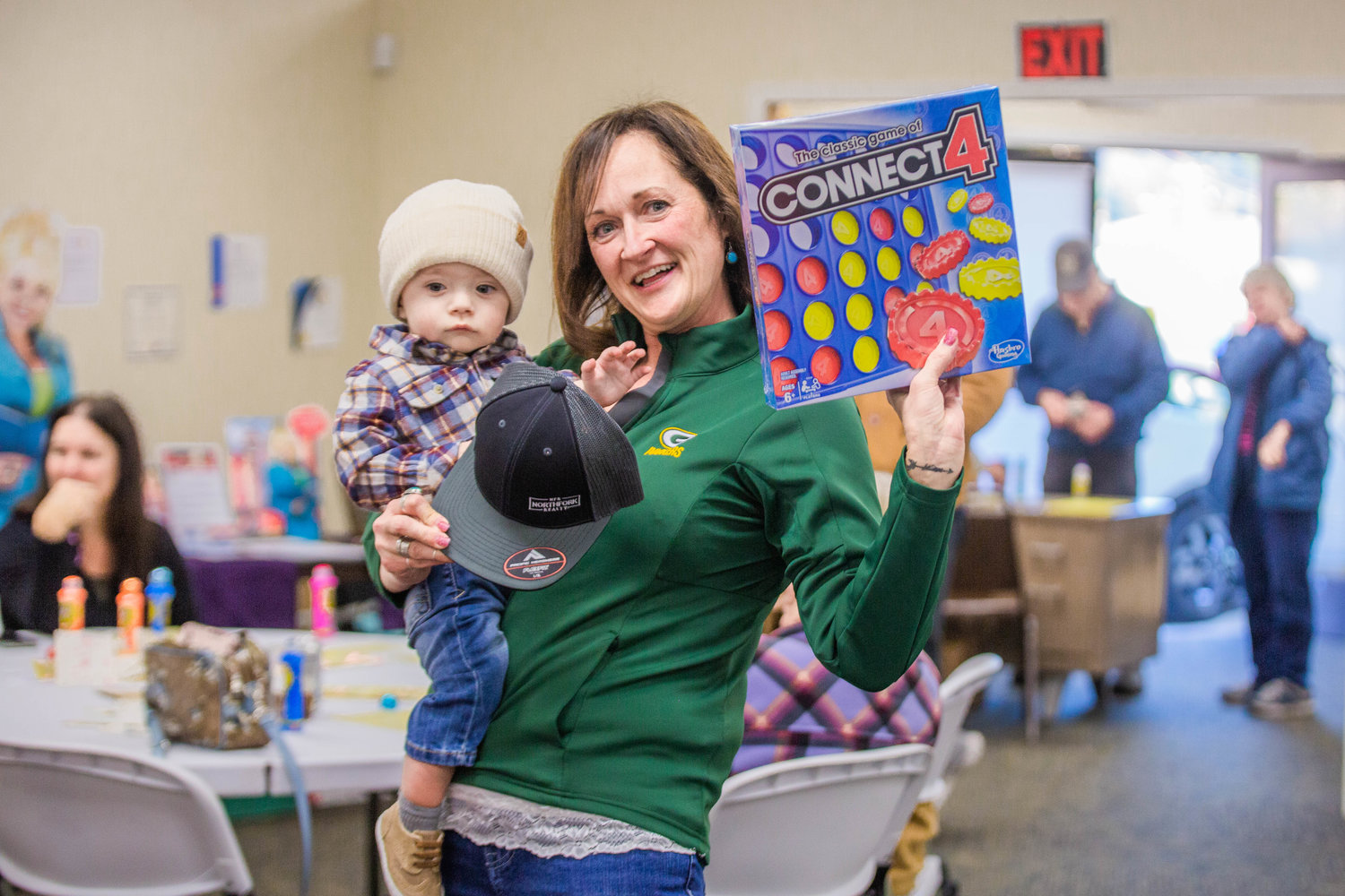 Sarah Lefebvre holds Eli Yukhno, an 11-month-old boy, and her prize of a new Connect 4 game after getting a bingo during the Twin Cities Rotary Club Turkey Bingo in the Chehalis Eagles building on Saturday afternoon.