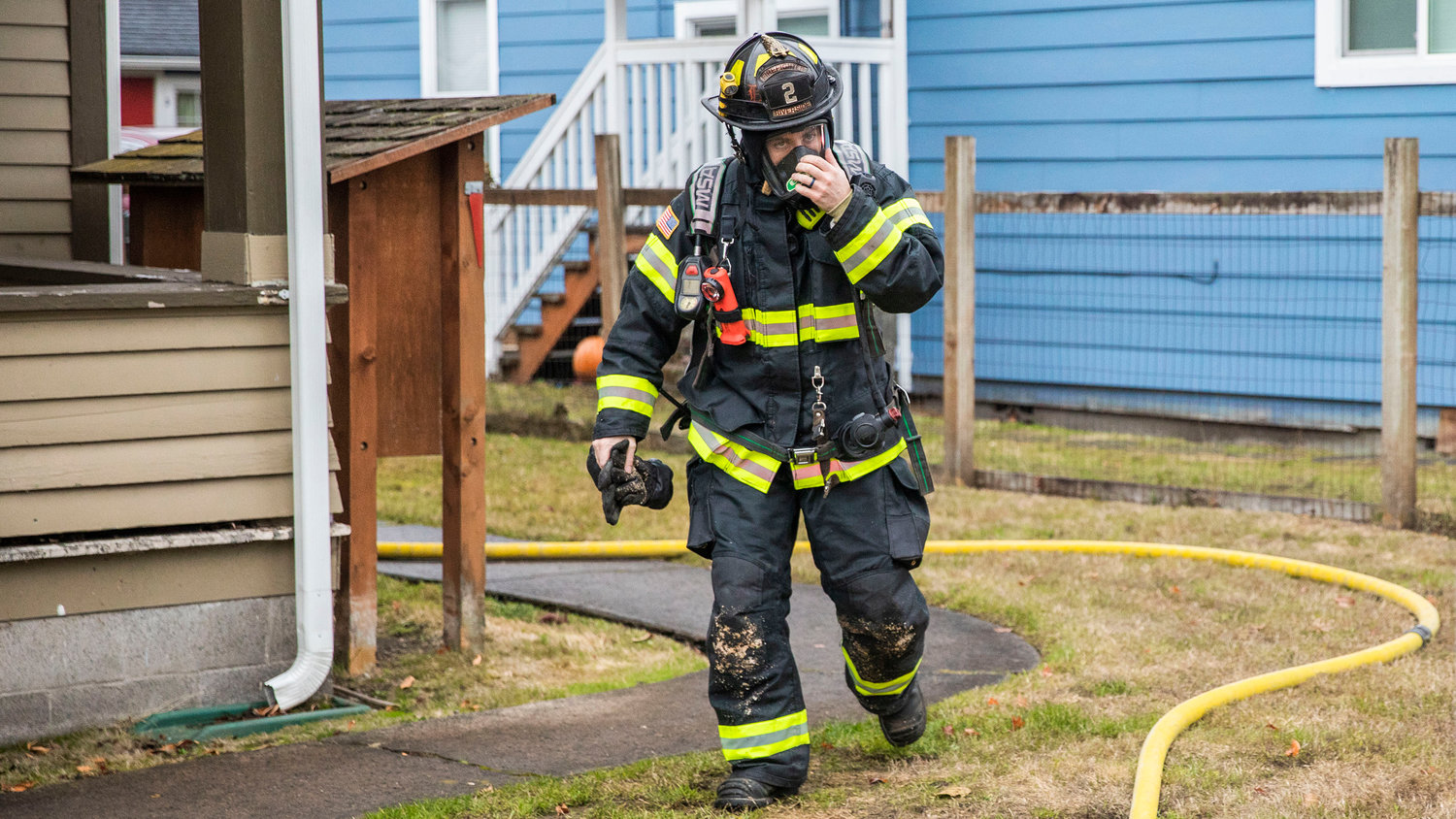 A Riverside firefighter adjusts his mask while responding to a residential fire in the 200 block of North Rock Street in Centralia on Friday.