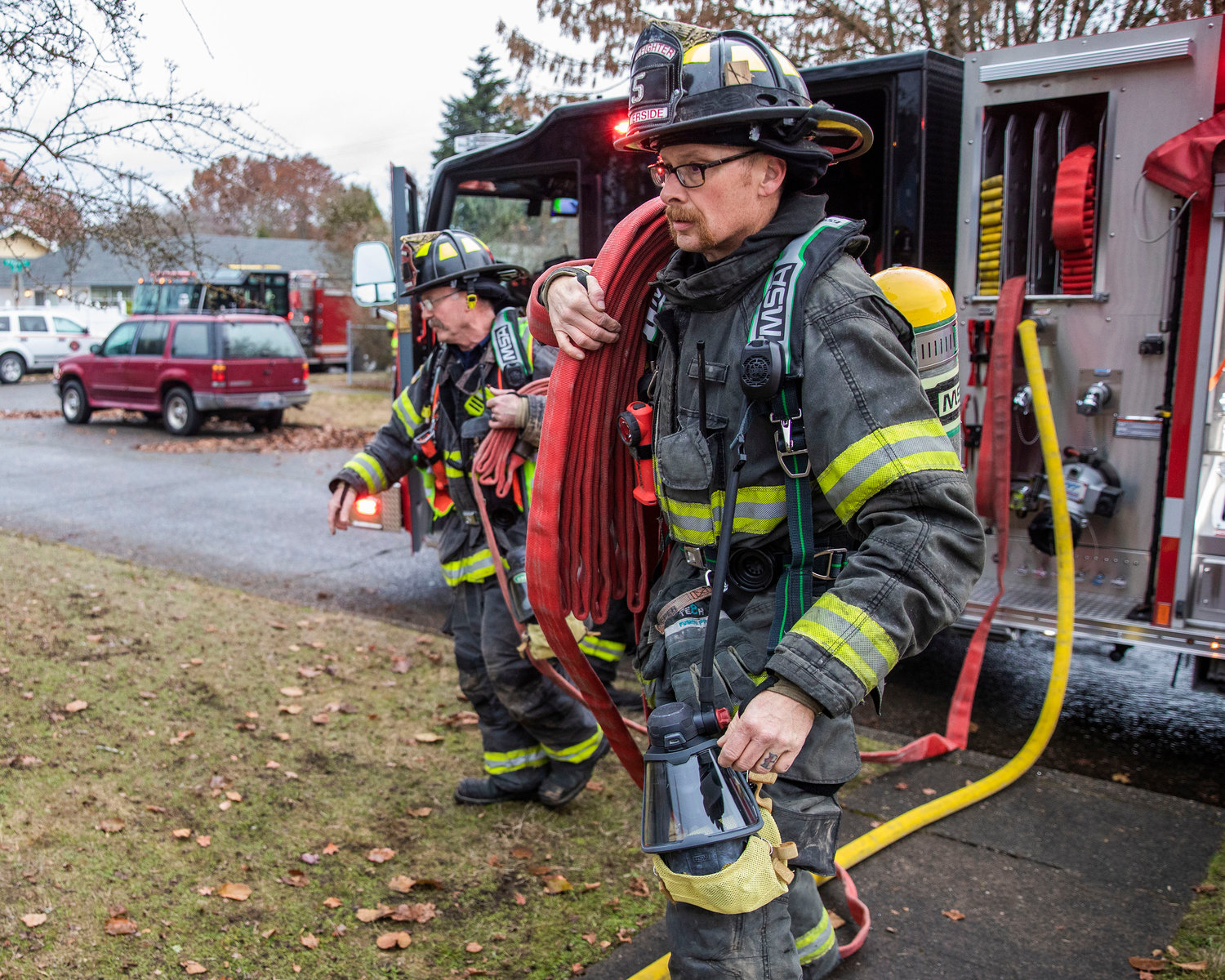 Riverside firefighters carry hoses into a building following a residential fire in the 200 block of North Rock Street in Centralia on Friday.