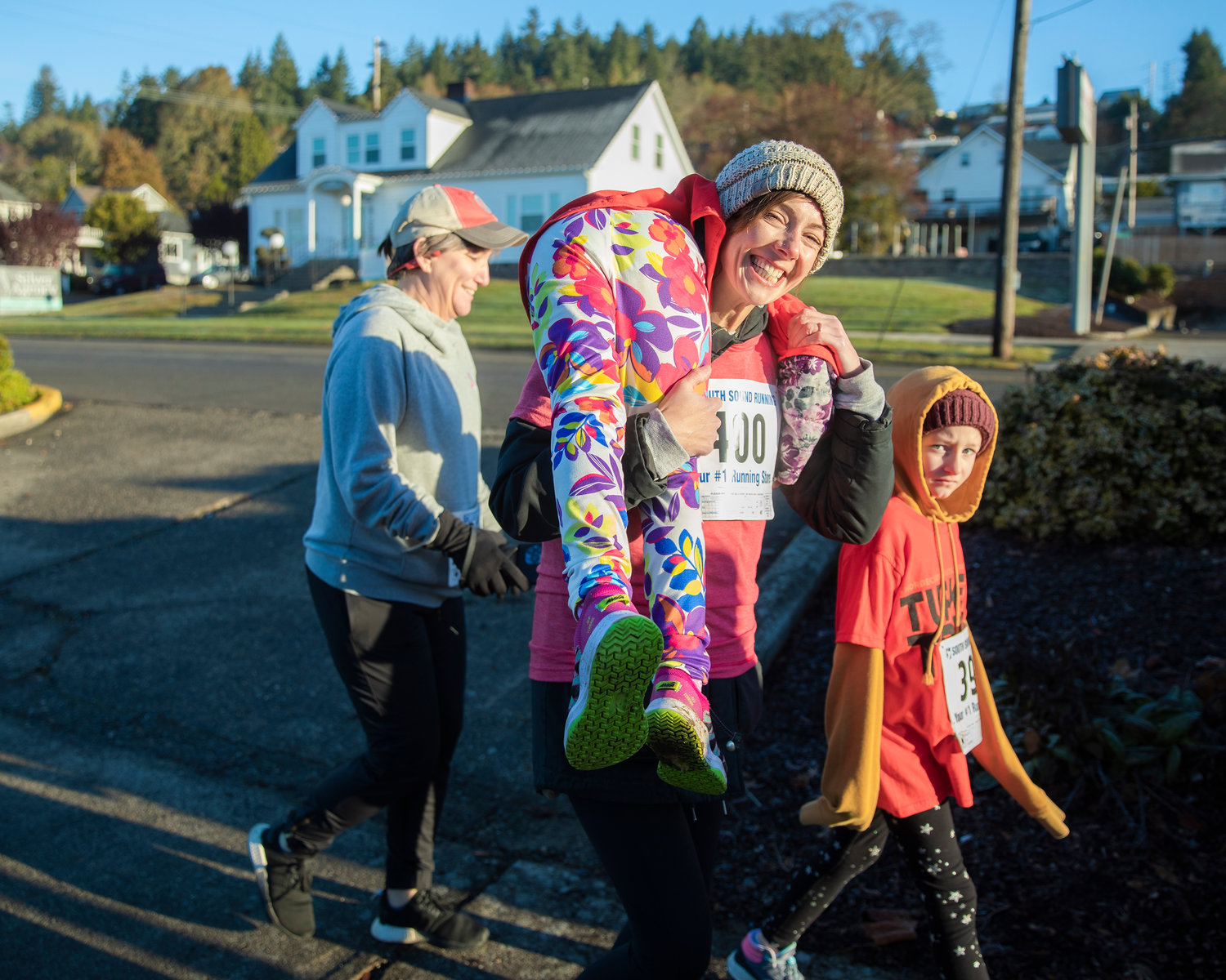 Amy Petersen smiles while carrying Ava, 6, through downtown Chehalis during the Turkey Trot 5K Thanksgiving morning.