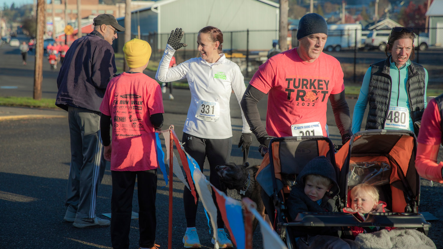 Participants smile and prepare to high-five as they make their way to the finish line during the Turkey Trot 5K Thanksgiving morning outside Thorbeckes in Chehalis.