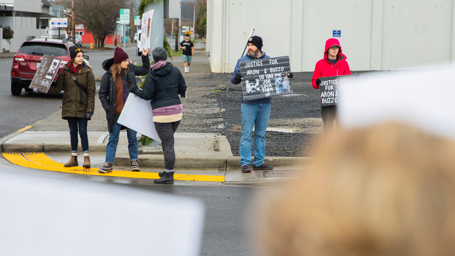 Friends of Aron Christensen hold signs outside the Lewis County Law and Justice Center while demanding justice in Chehalis on Sunday.