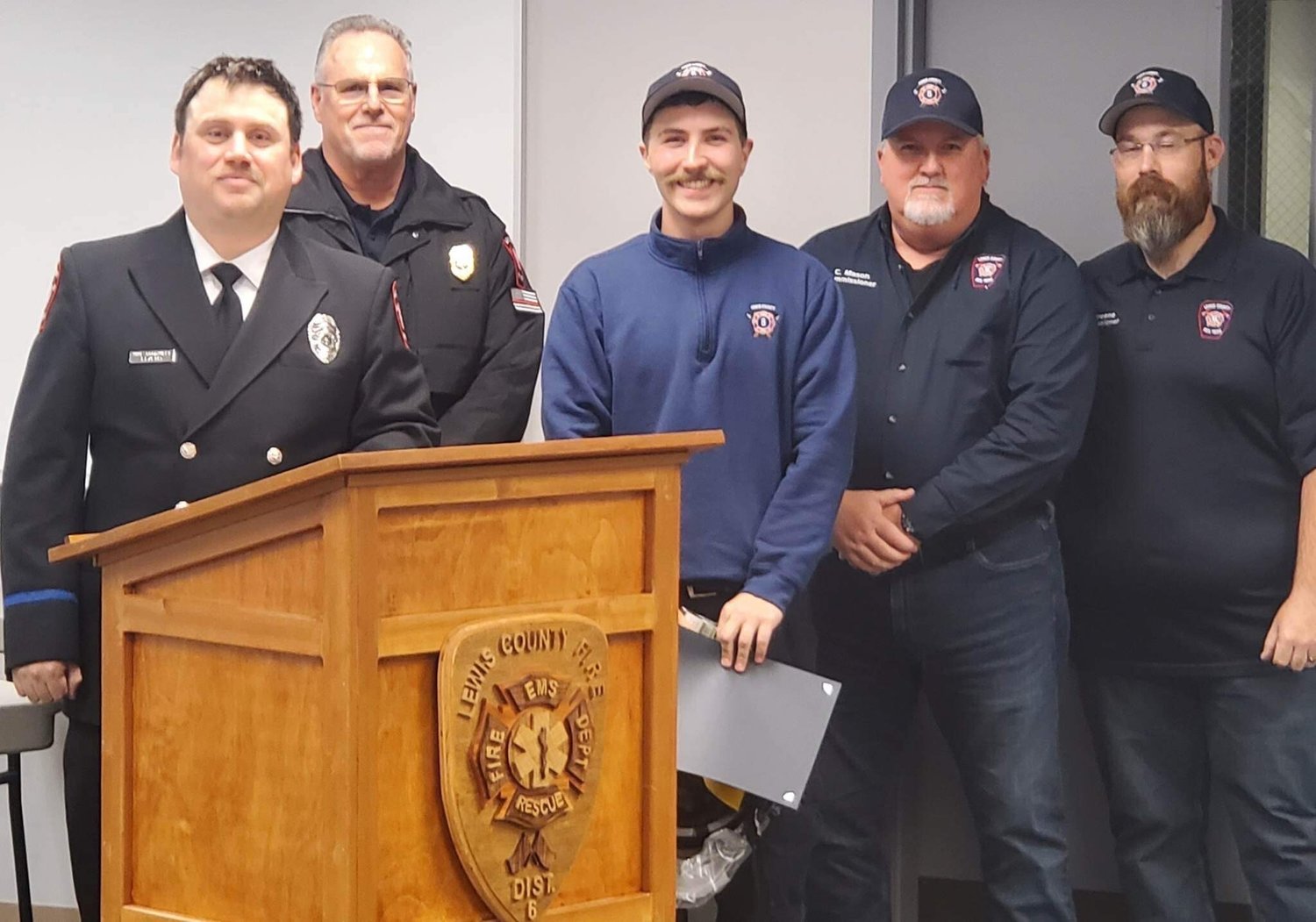 Recruit Graduate Mackenzie Kukas receiving his certificate, helmet and challenge coin. From left, firefighter Mike Goodwillie, Fire Chief Ken Cardinale, Kukas, Board Chair Colin Mason and Commissioner Greg Greene.