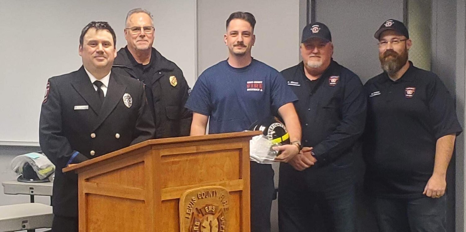 Recruit graduate Dayce Childress receiving his certificate, helmet and challenge coin. From left, firefighter Mike Goodwillie, Fire Chief Ken Cardinale, Childress, Board Chair Colin Mason and Commissioner Greg Greene.