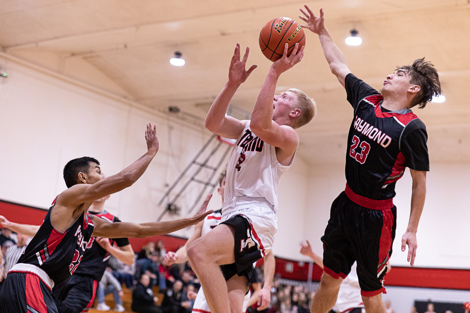 Tenino forward Austin Gonia drives for a layup, contested by Raymond's Iyven Perez Nov. 30.