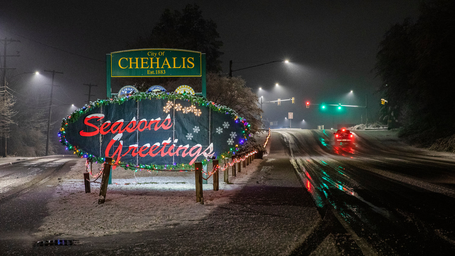 Snow falls as the “Seasons Greetings” sign in Chehalis is illuminated Sunday night.