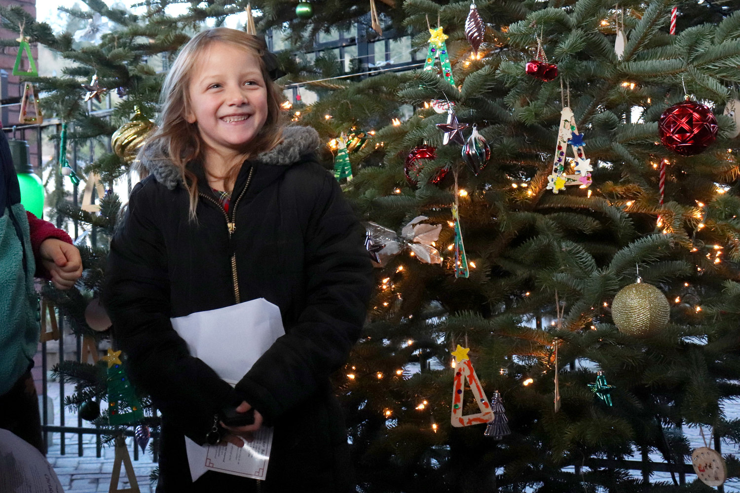Six-year-old Finley-Jean Filer smiles after lighting the City of Chehalis’ Christmas tree outside of the Lewis County Historical Museum on Saturday.