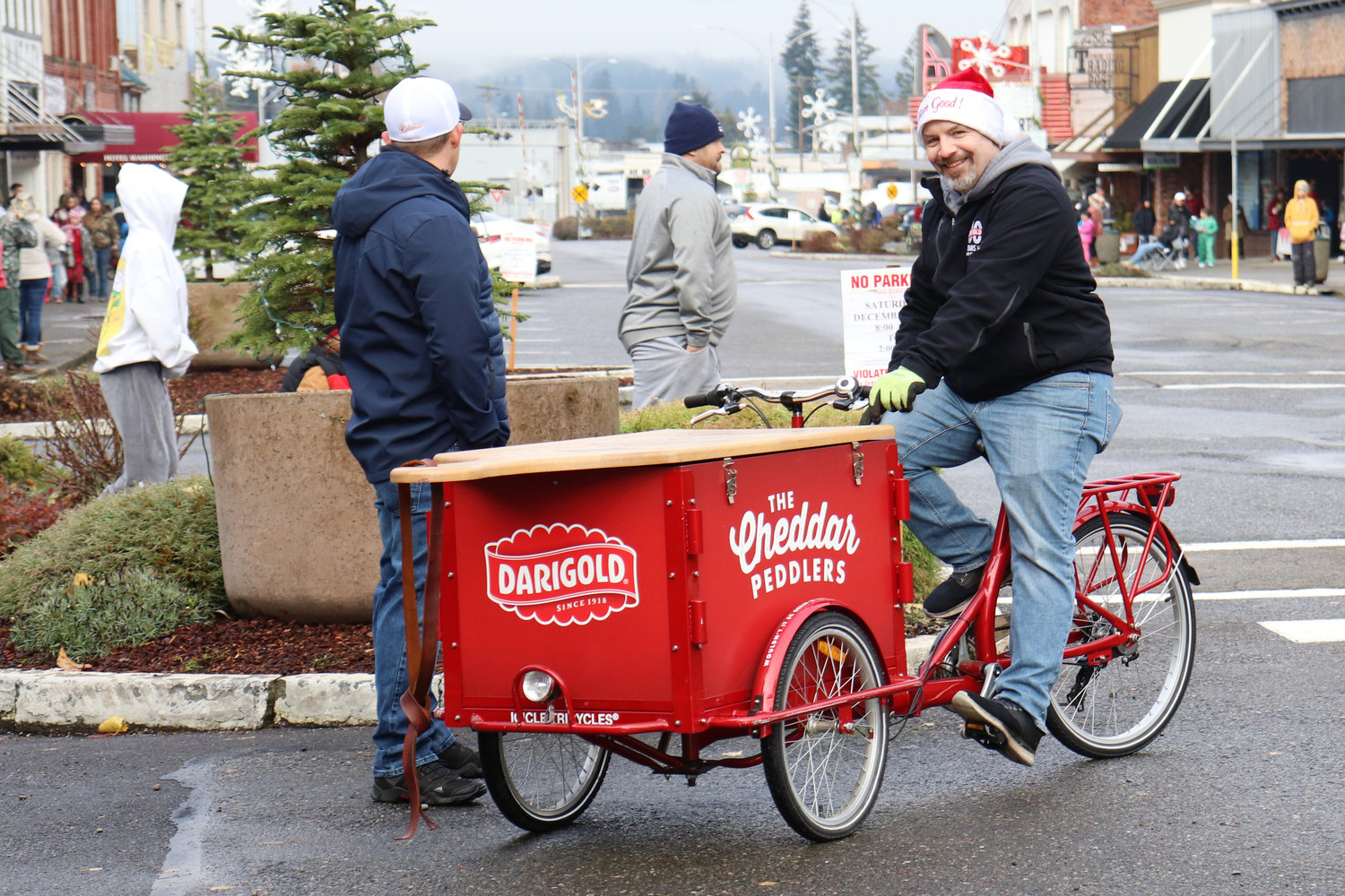 A volunteer delivers free milk, courtesy of Darigold, via the Cheddar Peddler to Santa Parade-viewers in downtown Chehalis on Saturday.