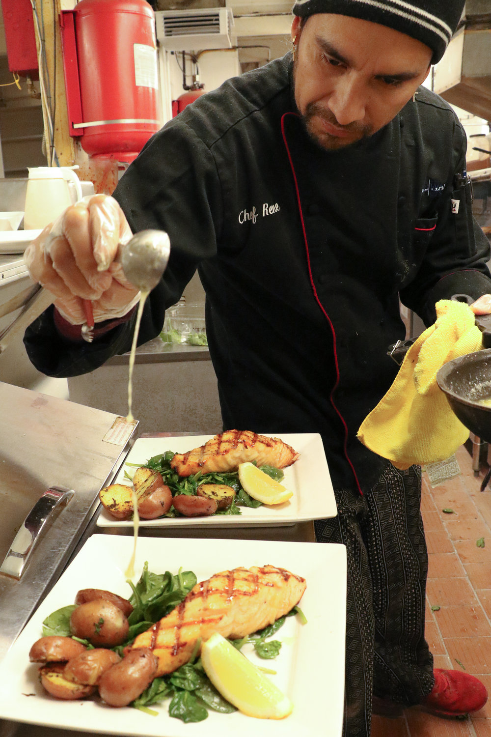 Chef Eyner "Rene" Cardona garnishes eight ounce king salmon filets with butter sauce before sending them out for sampling on Monday morning.