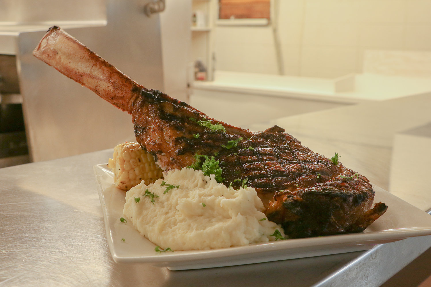 Prepared by Chef Eyner "Rene" Cardona, a tomahawk steak sits atop a pile of house-made mashed potatoes and grilled-corn-on-the-cob at the menu sampling for Cardona's new restaurant in Chehalis, Ocean Prime.