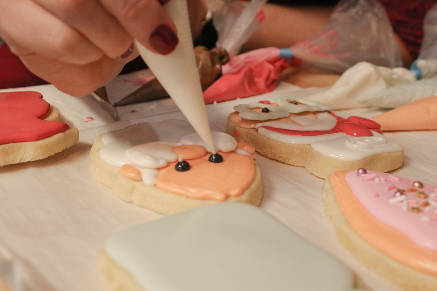 Anna Martin, owner of Anna's Bakery, adds a glimmer to the eyes of a Santa sugar cookie she was decorating during a royal icing cookie decorating class she hosted at the Dandelion Creative Space on Sunday.