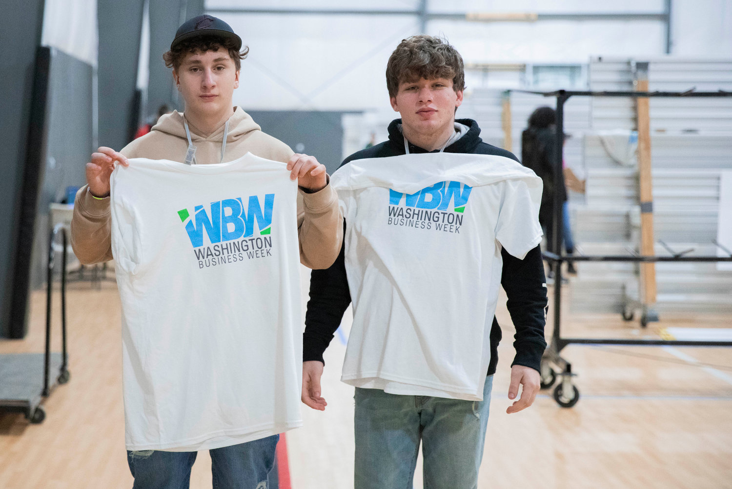 Centralia High School students Tim Eberly and Dylan Mock hold up their Washington Business Week shirts Wednesday morning at the Northwest Sports Hub.