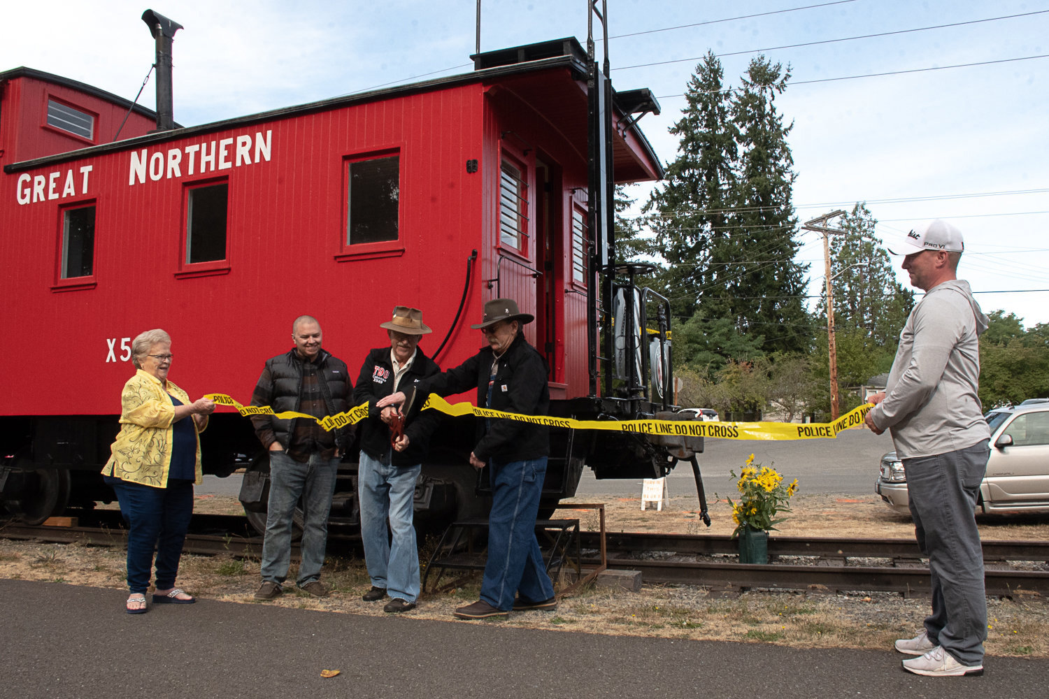 Don Bowman and Jan Wigley cut a make-shift ribbon held by Tenino City Council Members Linda Gotovac and Jason Lawton while Tenino Mayor Wayne Fournier looks on during the city's Tenino Railroad Day event in September 2022.