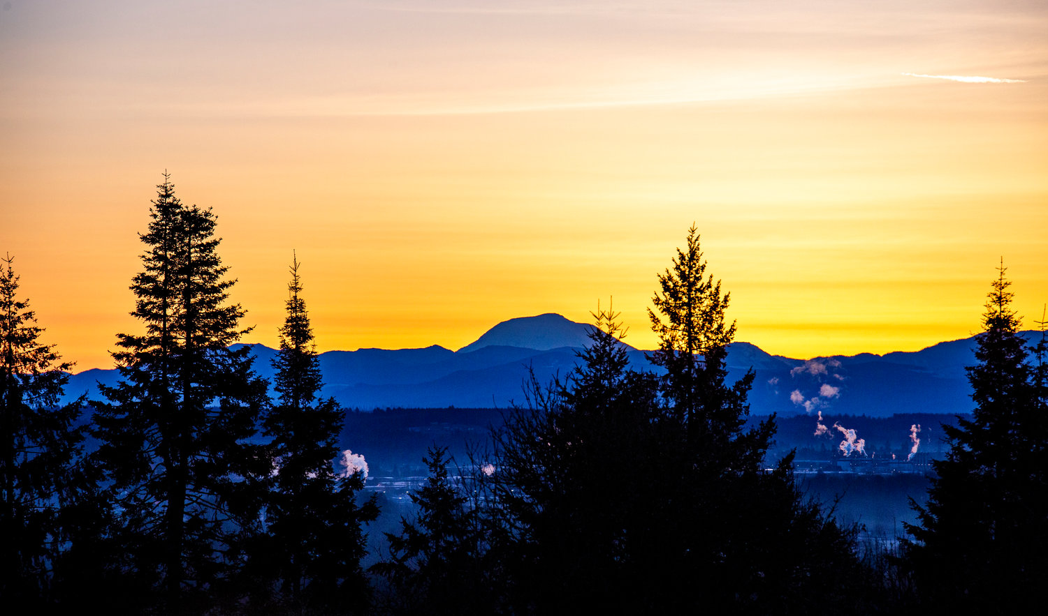 Mount Adams is backlit by the sunrise and an orange sky on Monday morning, seen from between Chehalis and Adna.