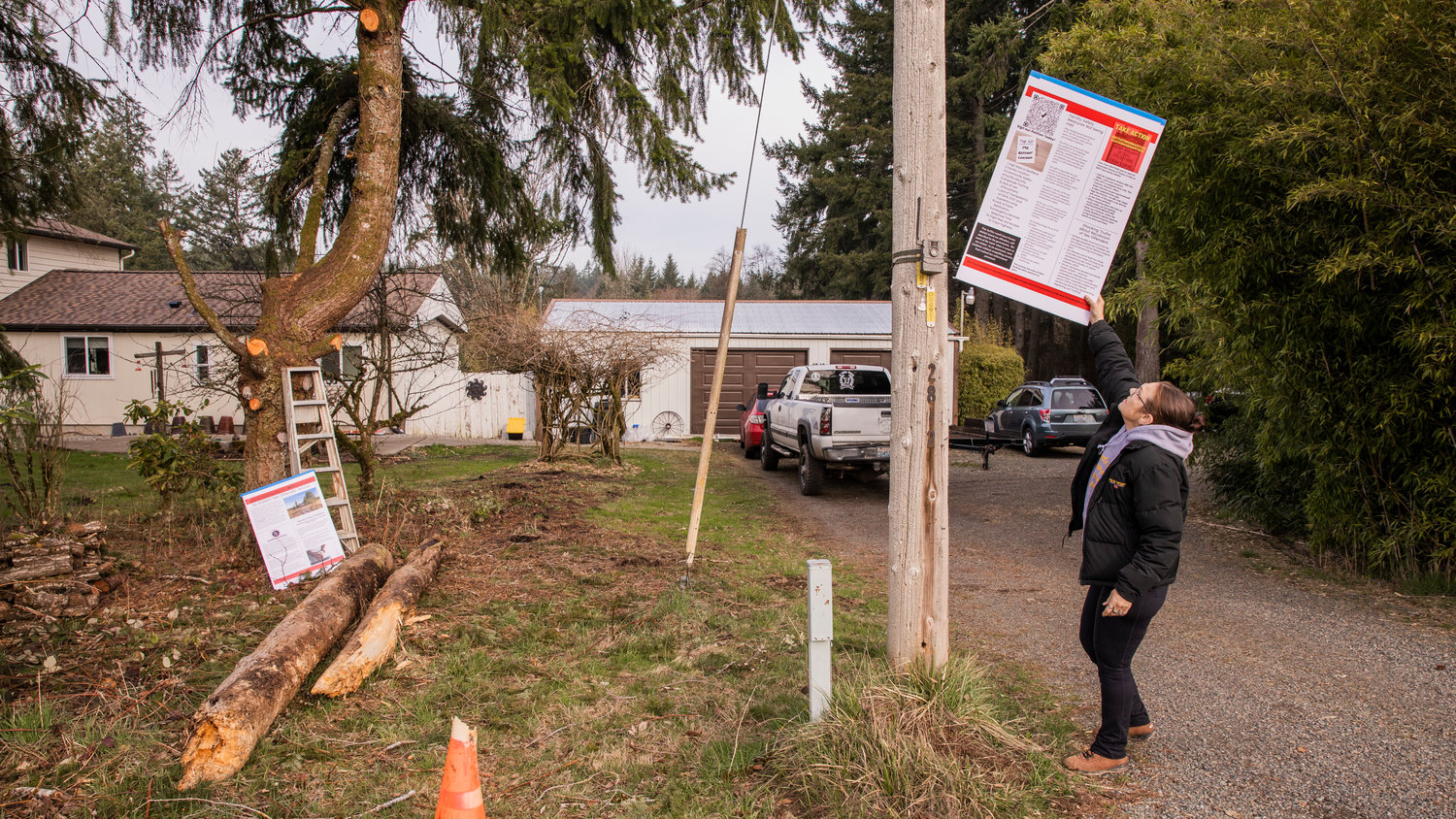 Kim Crist, who lives across the street from the Supreme Living facility, looks to put up signage above a live trail camera facing out from her property Wednesday morning.