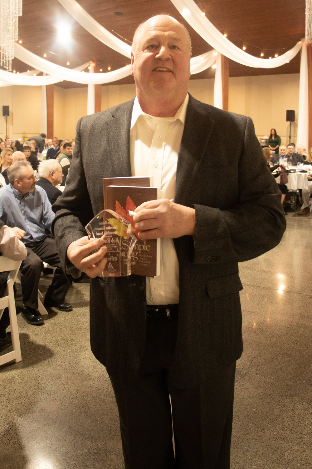 Adna resident and salmon conservationist Bob Russell poses with the Russ Mohney award as well as two copies of Mohney's book Friday night at the Economic Alliance of Lewis County's 40th annual banquet.