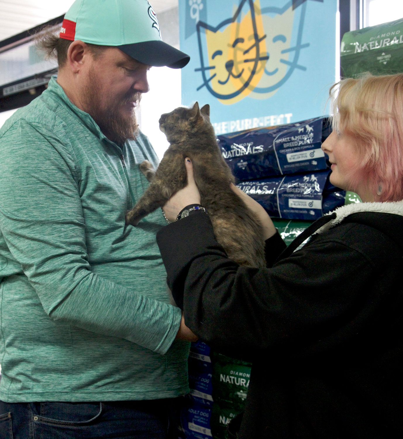 A volunteer hands Viv, a 1-year-old diluted calico, to her new owner at Petsense in Chehalis on Saturday.