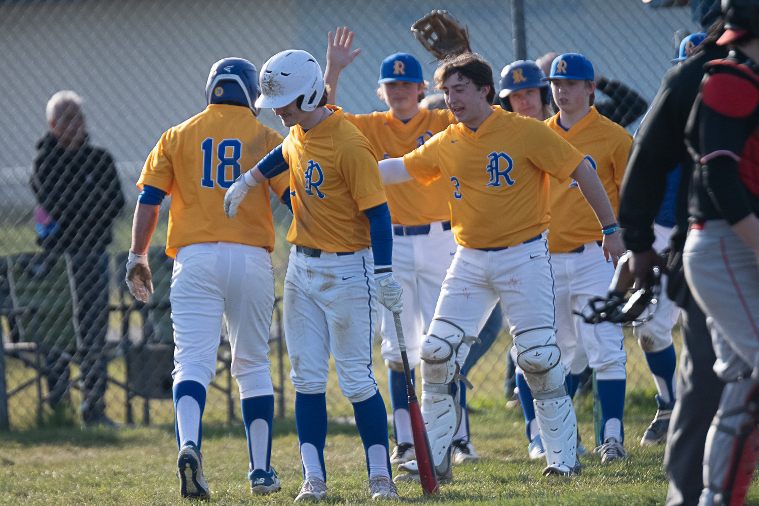 The Rochester dugout welcomes back Mason Armstrong (18) after he scored a run in the bottom of the second inning of the Warriors' 15-6 win over R.A. Long on March 16.