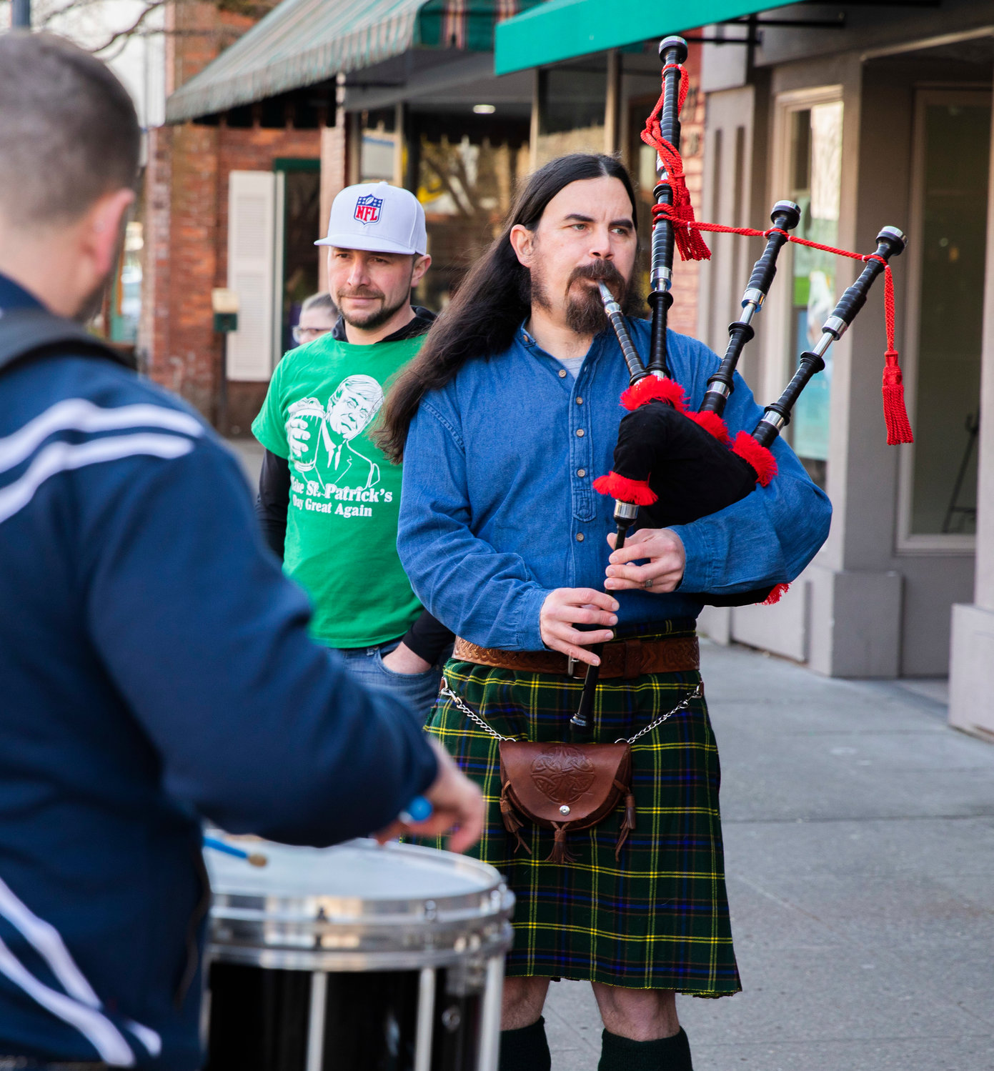 Visitors walk outside O’Blarney’s Irish Pub on Thursday to listen to music as James Roush plays bagpipes and Chris McKee plays drums in downtown Centralia.