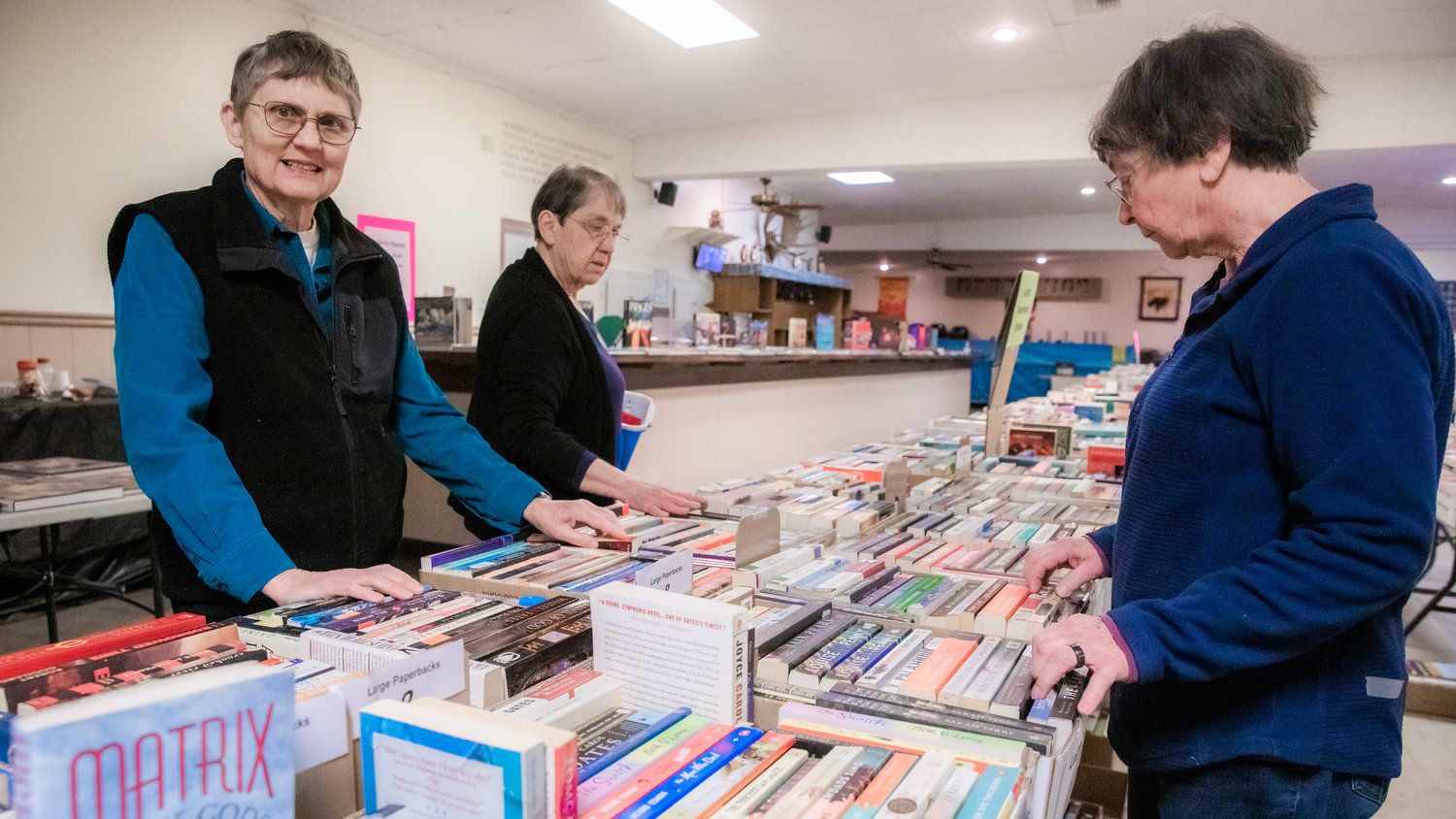Donna Loucks, far left, talks about the history of the AAUW Used Book Sale which began over 40 years ago and is being held at the Moose Lodge in Centralia for the first time.