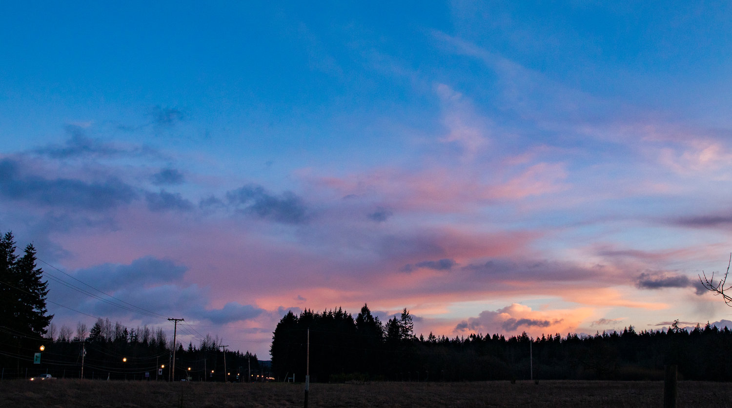 At the county line between Grays Harbor and Thurston counties on Saturday at sunset, clouds cast colors over streetlights.
