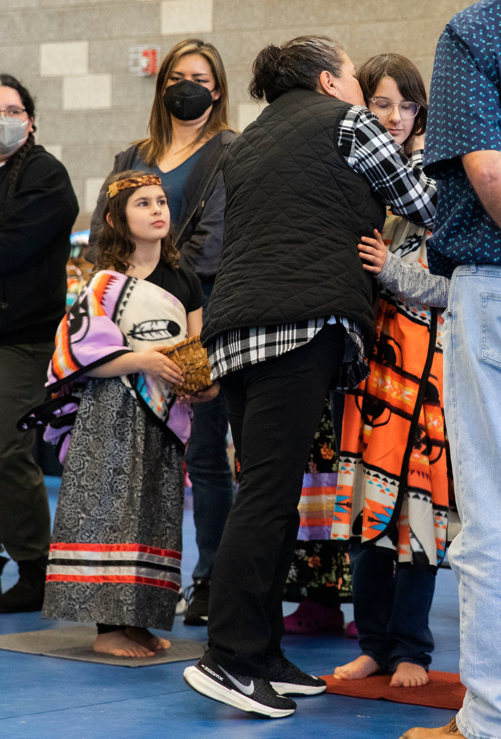 Jack Kesler is kissed an embraced as he and his sister Clara Kesler are welcomed into the Hazel Pete family as gatherers at the Chehalis Tribe Community Center in Oakville on Saturday.