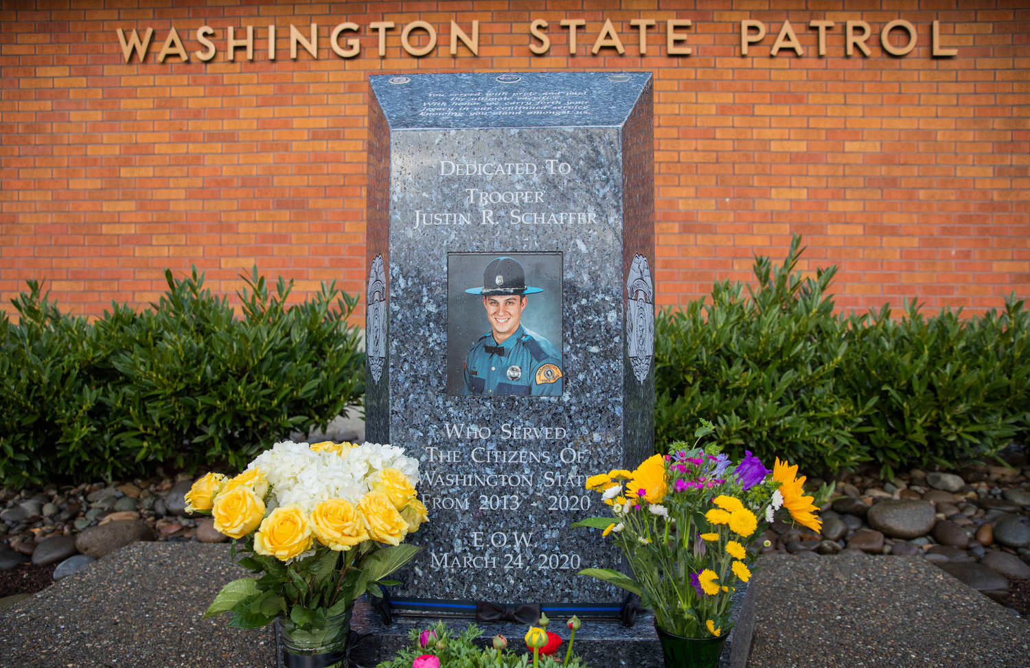 Flowers are arranged around a memorial for Trooper Justin Schaffer Friday morning at the Chehalis Washington State Patrol office.