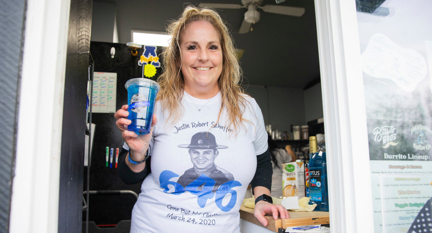 Angie Krause, formerly known as Angie Humphrey, smiles and holds up a “Trooper” drink available at Skull and Crossbones Coffee Co. in honor of Justin Schaffer Friday morning in Adna. On Friday, a portion of each sale went toward the Justin Schaffer Scholarship Fund in Adna. Schaffer died three years ago after he was struck by a fleeing vehicle while attempting to set spike strips. Skull & Crossbones Coffee Co. is located at 109 Bunker Creek Road across from Adna Grocery. The coffee stand is open from 6 a.m. to 3:30 p.m. on weekdays and from 7 a.m. to 3 p.m. on weekends.