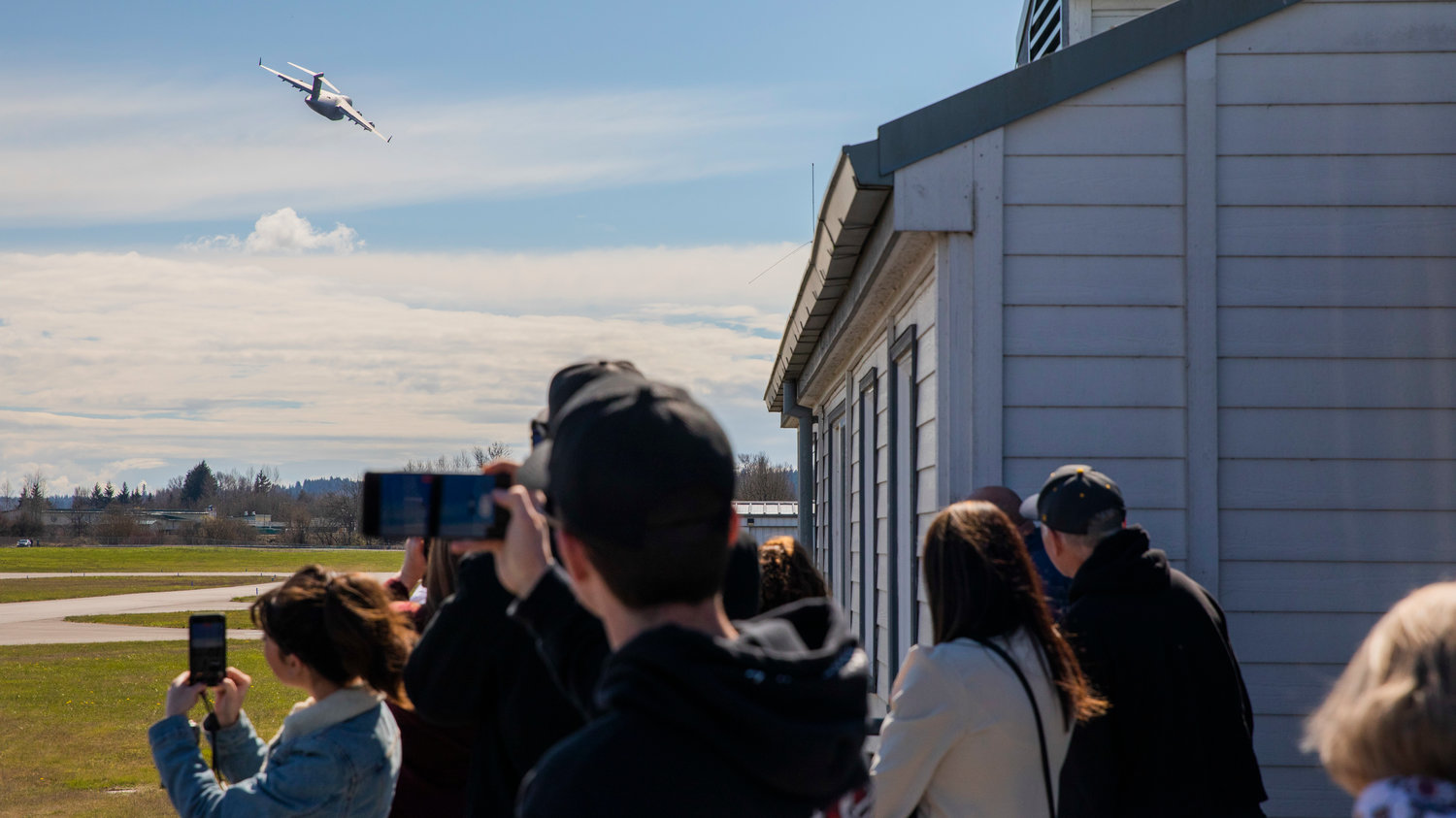 Visitors watch and record as a C-17 completes a low flyover at the Chehalis-Centralia Airport Wednesday afternoon in Chehalis.