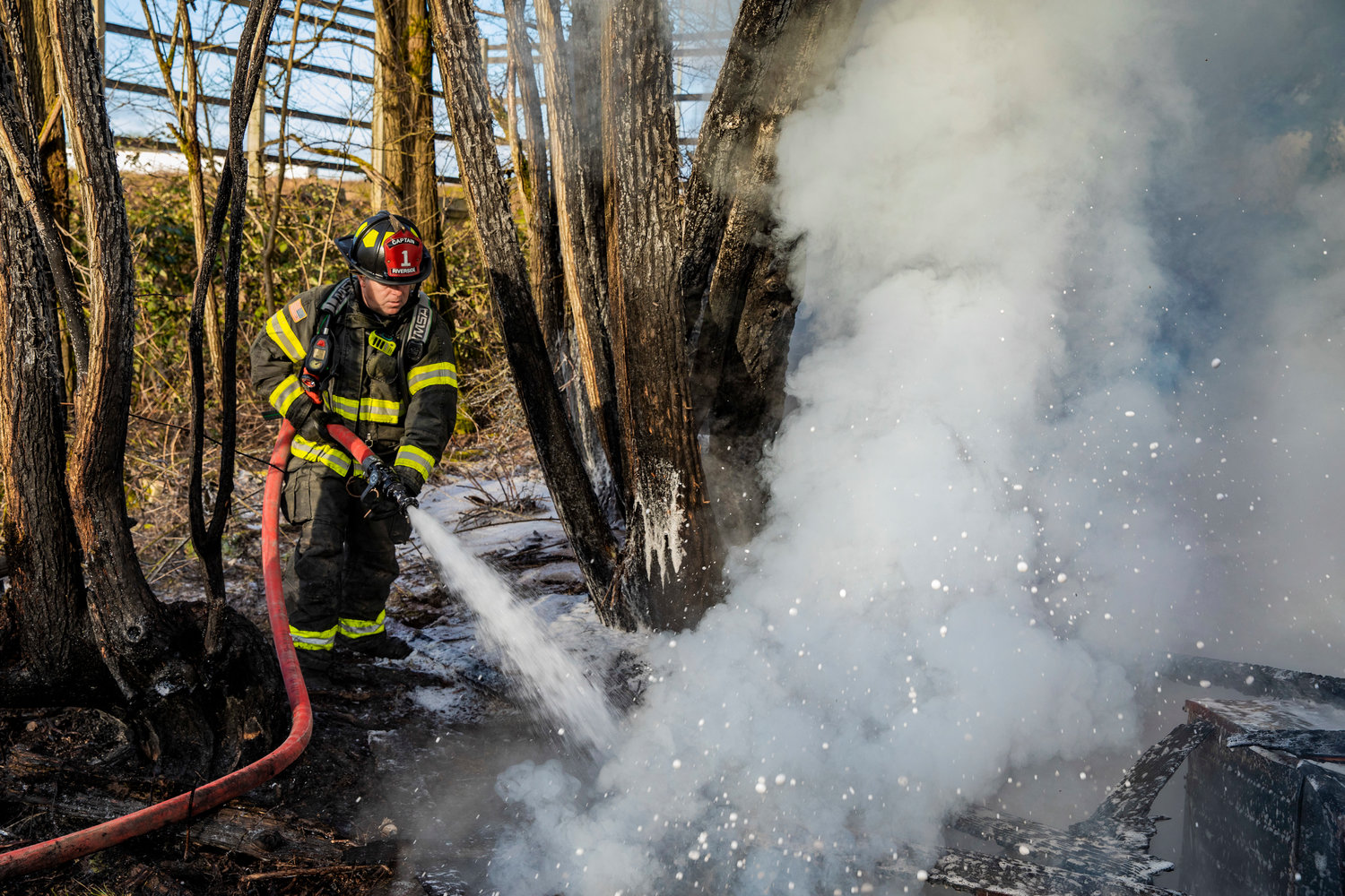 Captain Casey McCarthy, with Riverside Fire Authority, uses a hose to extinguish flames at an outbuilding that was supposed to be unoccupied along Long Road in Centralia Thursday morning. That Chronicle had not learned the cause of the fire as of Friday afternoon. There were no injuries reported.