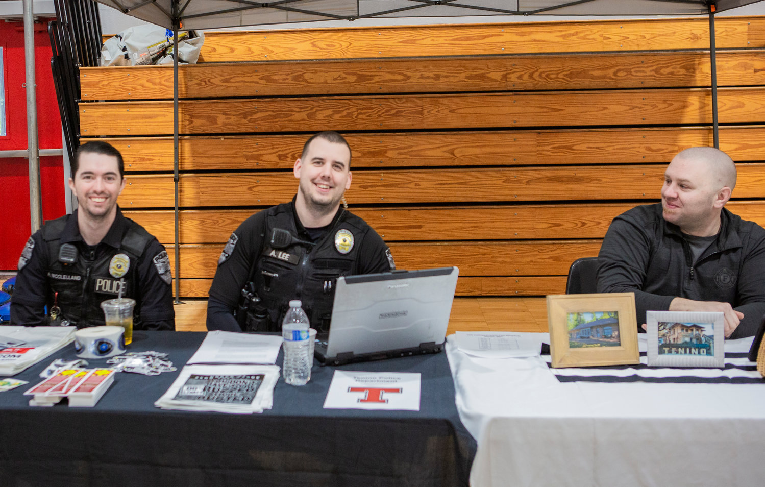 Tenino police officers Alec McClelland and Aaron Lee smile as Mayor Wayne Fournier looks toward them during a college and career fair at Tenino High School on Thursday.