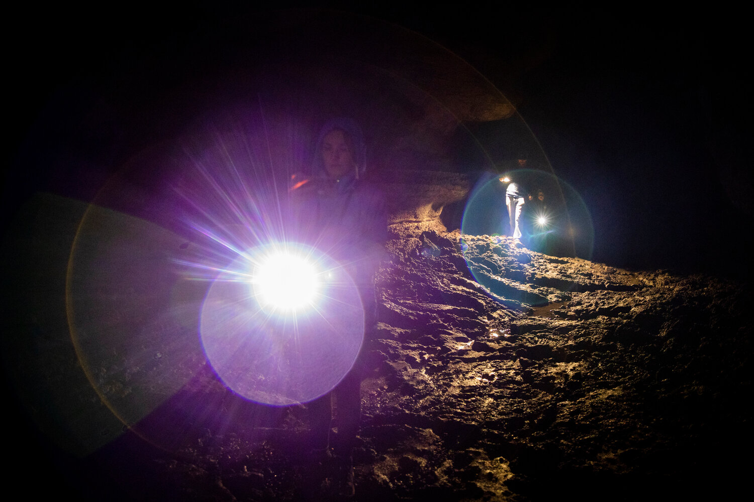 Hikers use flashlights to illuminate a path through the Ape Cave in Cougar on opening day Thursday, May 18.