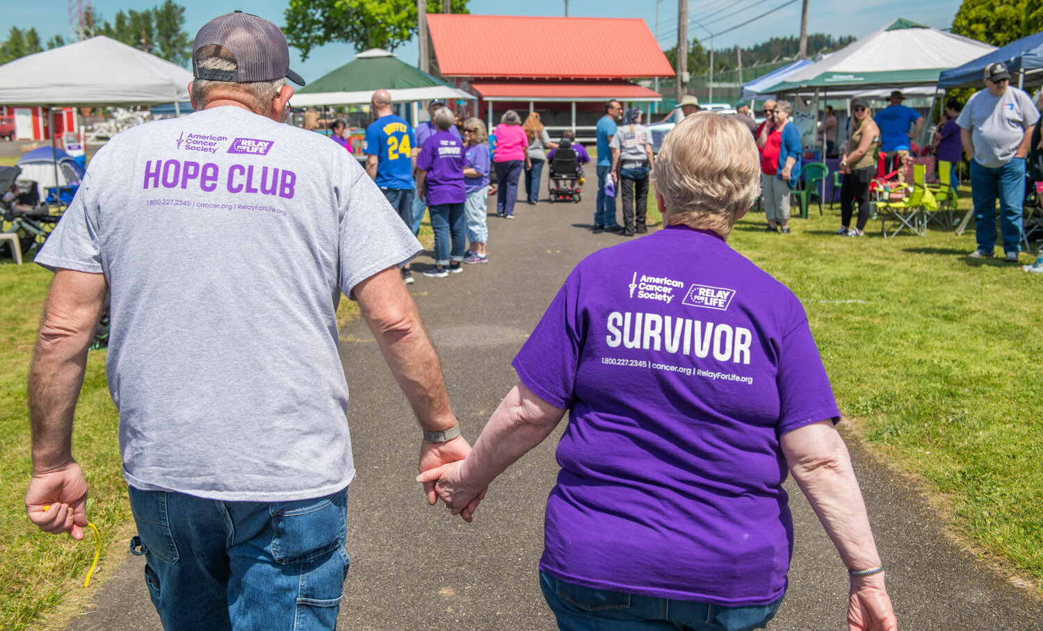 Survivor Katie Foss, right, holds hands with her husband John during a Relay For Life walk at the Southwest Washington Fairgrounds on Saturday, May 20.