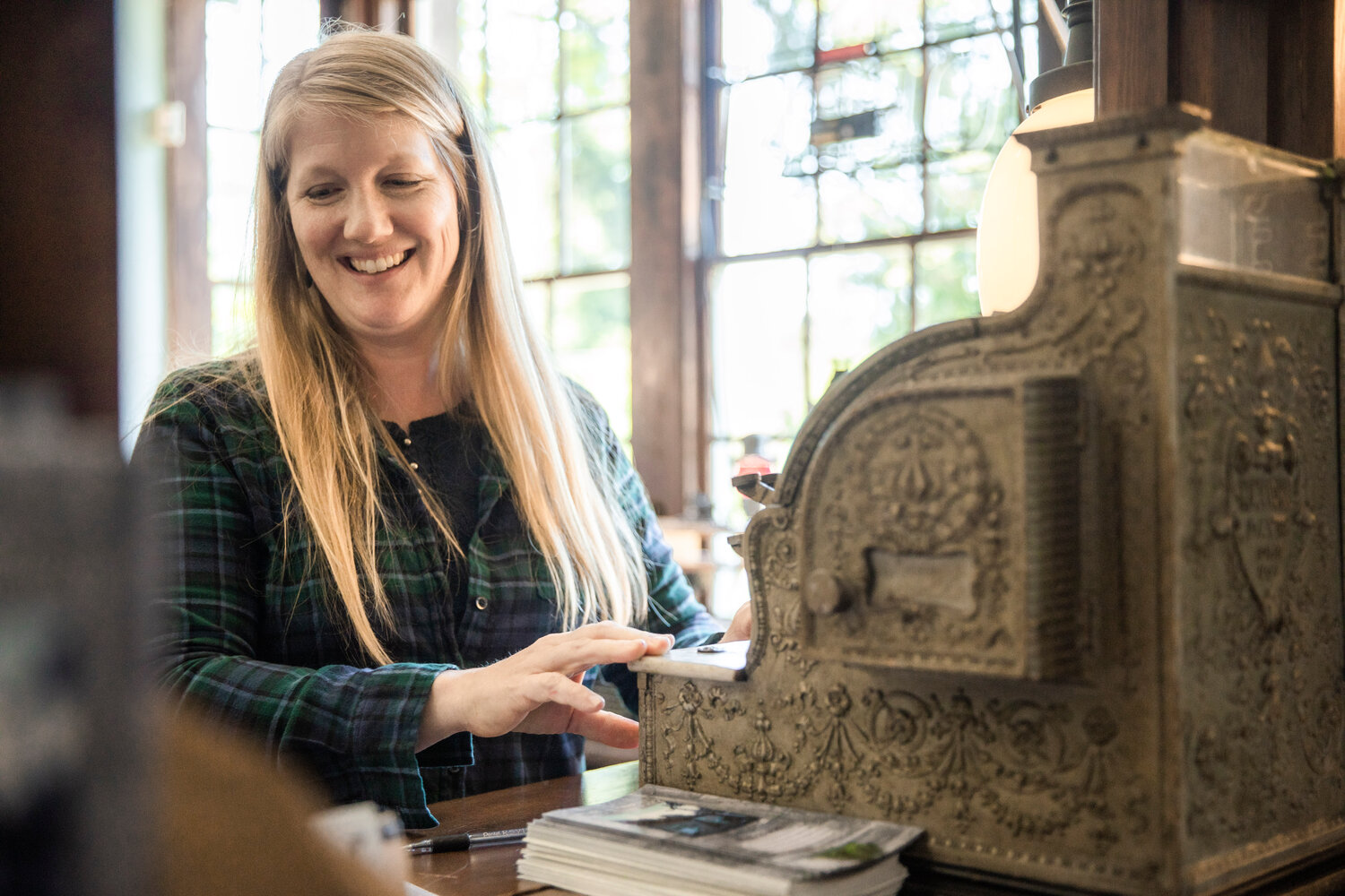 Tenino PARC (parks, arts, recreation and culture) Director Jessica Reeves-Rush smiles as an old cash register dings inside the Tenino Depot Museum on Friday after the sale of a new book she co-authored with the city historian celebrating the 150th birthday of the Stone City.