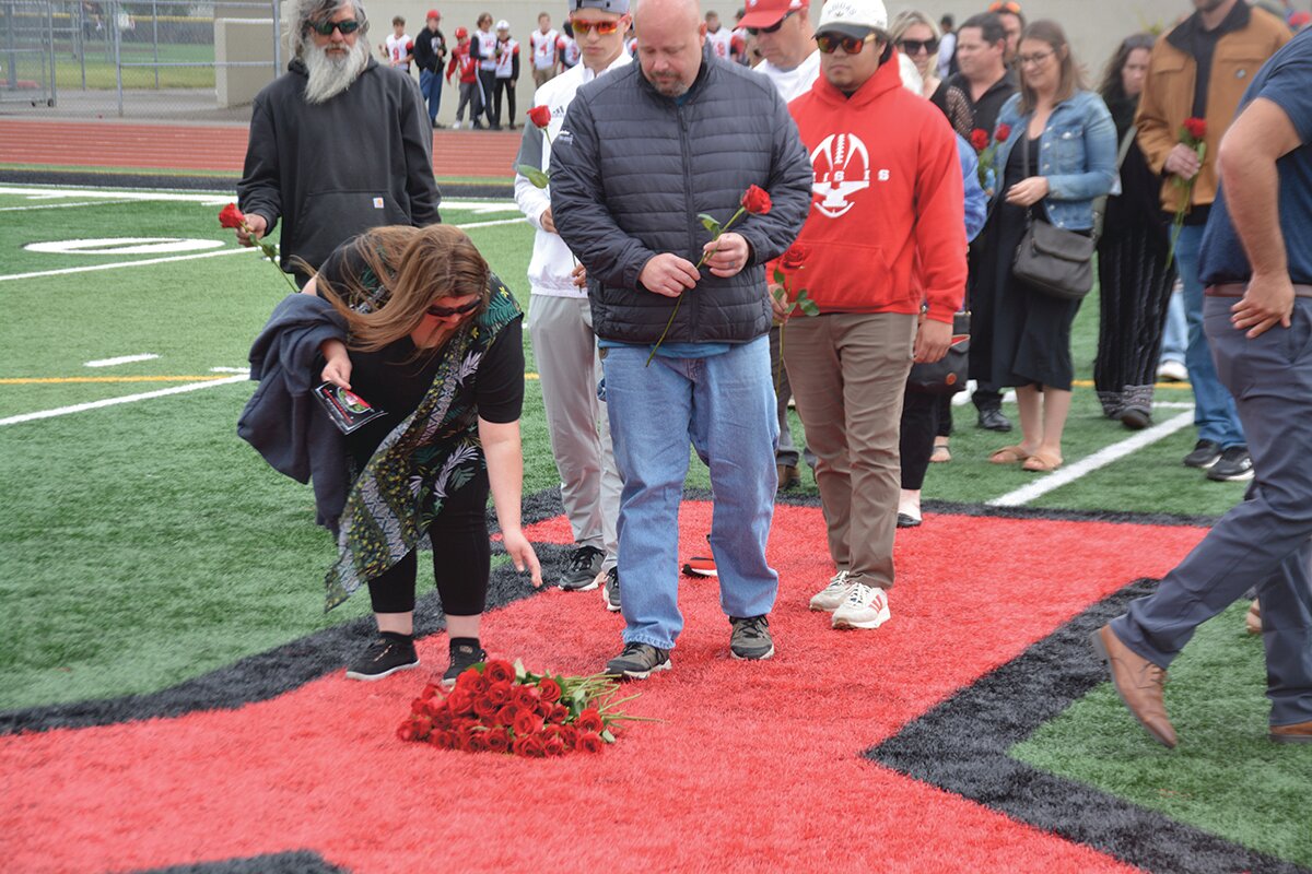 A memorial attendee leaves behind a rose in honor of Shawn Jemtegaard.