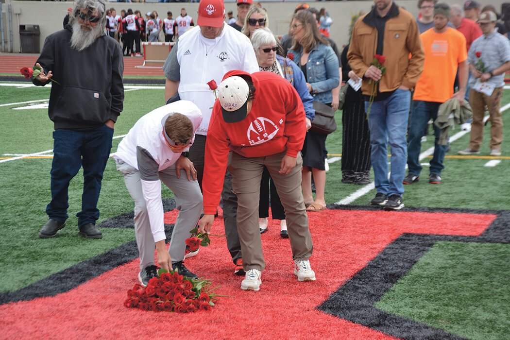 Yelm coaches Jacob Nolan and Brandon Thompson place roses mid-field in honor of Shawn Jemtegaard.