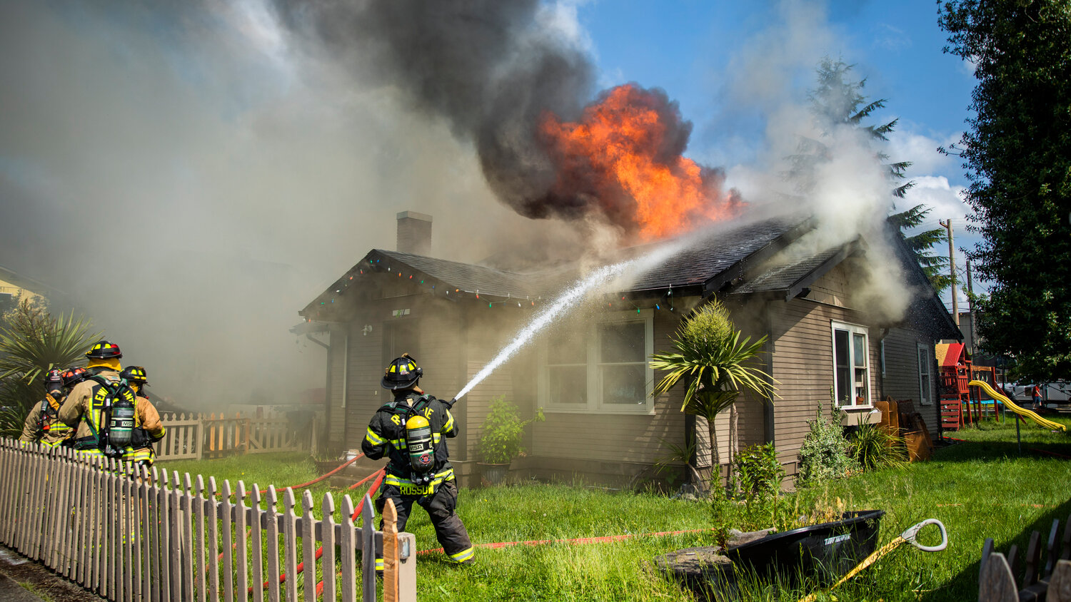 Lewis County and Riverside firefighters work to douse flames as a column of smoke rises from a residence in the 800 block of Centralia College Blvd. on Wednesday, May 24.