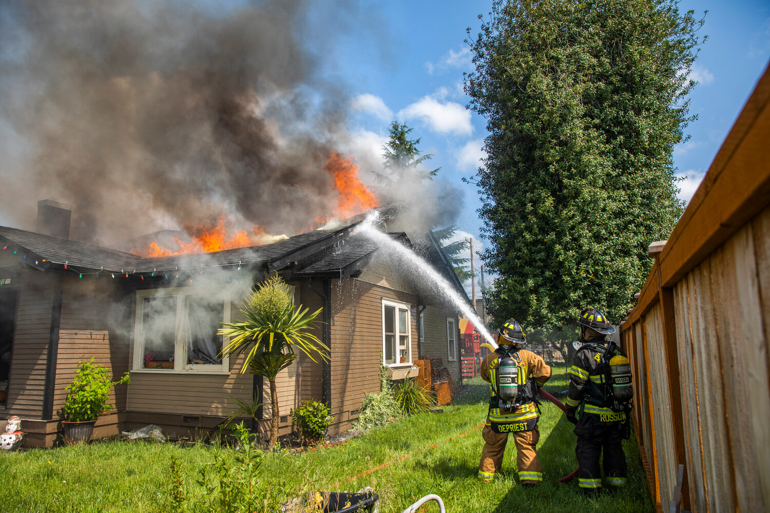 Lewis County and Riverside firefighters work to douse flames as a column of smoke rises from a residence in the 800 block of Centralia College Blvd. on Wednesday, May 24.