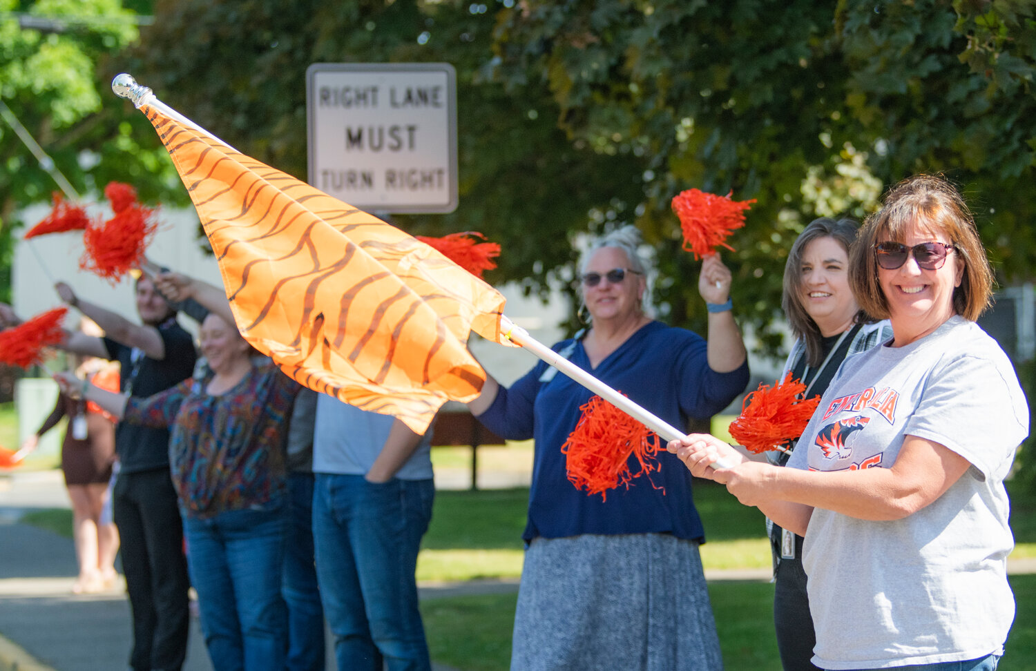Centralia School District staff cheer, hold pom-poms and wave flags as the high school softball team has a celebratory send-off procession on Thursday morning.