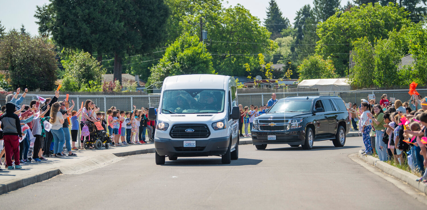 Students and staff of Centralia’s Fords Prairie Elementary School cheer and wave signs while the high school’s state-bound softball team parades through the parking lot on Thursday morning.