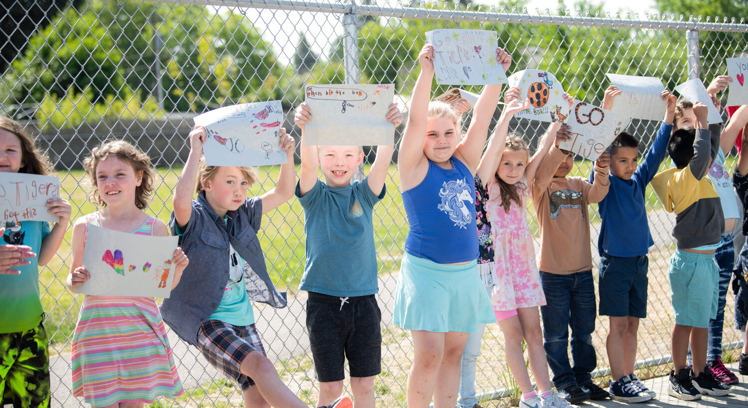 Students at Centralia’s Fords Prairie Elementary School cheer and wave signs while the high school’s state-bound softball team parades through the parking lot on Thursday morning.